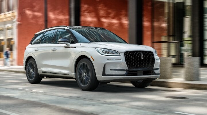 A white 2025 Lincoln Corsair® SUV with the Jet Appearance Package is being driven through a city.| Steet-Ponte Lincoln in Yorkville NY