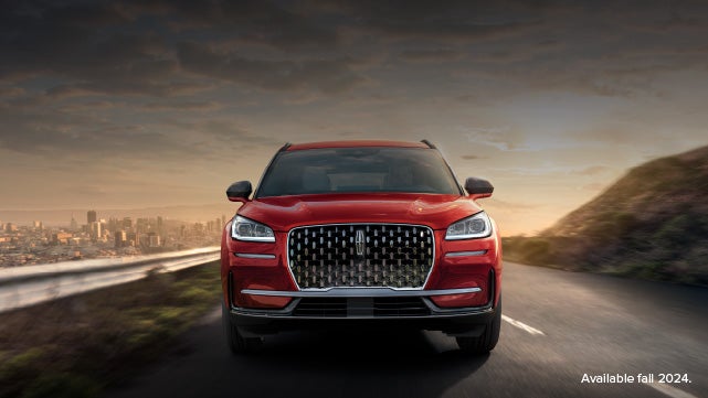 A 2025 red Lincoln Corsair® SUV is being driven down a road at sunset. | Steet-Ponte Lincoln in Yorkville NY