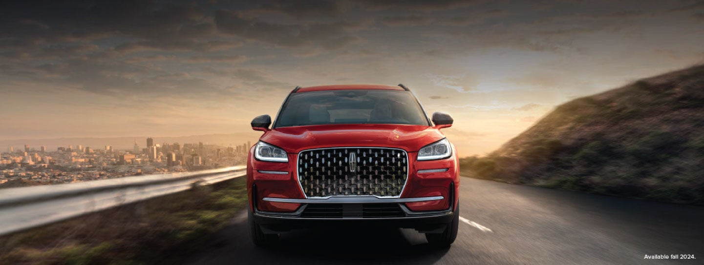 A 2025 red Lincoln Corsair® SUV is being driven down a road at sunset. | Steet-Ponte Lincoln in Yorkville NY