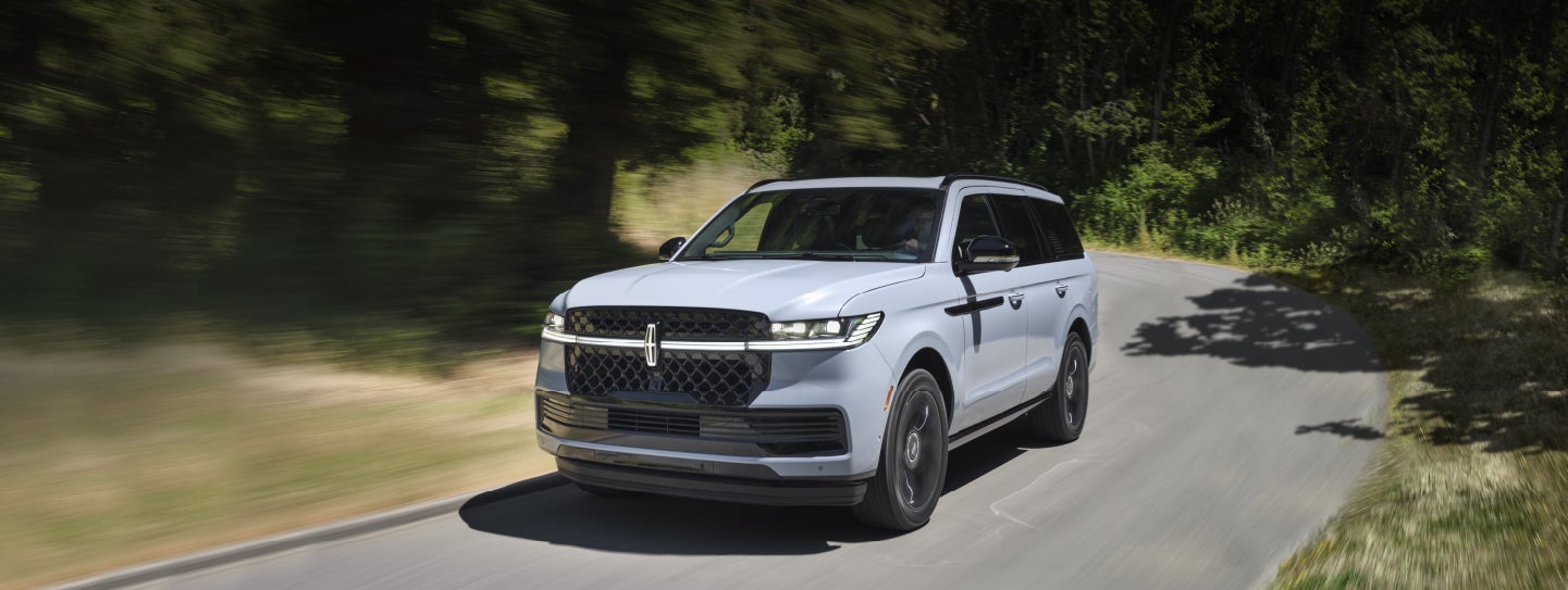 A 2025 Lincoln Navigator® SUV is being driven on a country road.
