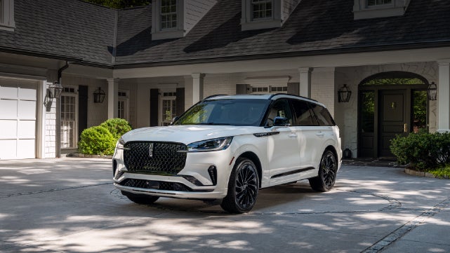 A white 2026 Lincoln Aviator® SUV is parked in the driveway of a luxury home. | Steet-Ponte Lincoln in Yorkville NY