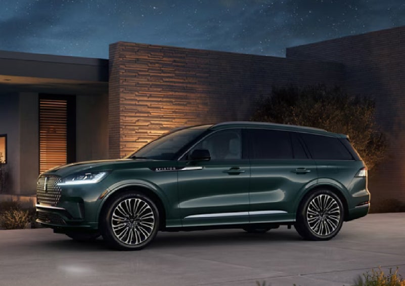 A green 2027 Lincoln Aviator® SUV is parked outside a contemporary home. | Steet-Ponte Lincoln in Yorkville NY