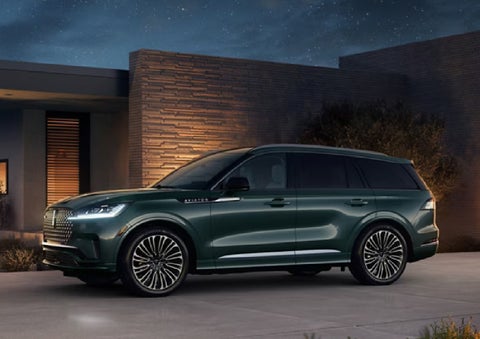 A green 2027 Lincoln Aviator® SUV is parked outside a contemporary home. | Steet-Ponte Lincoln in Yorkville NY