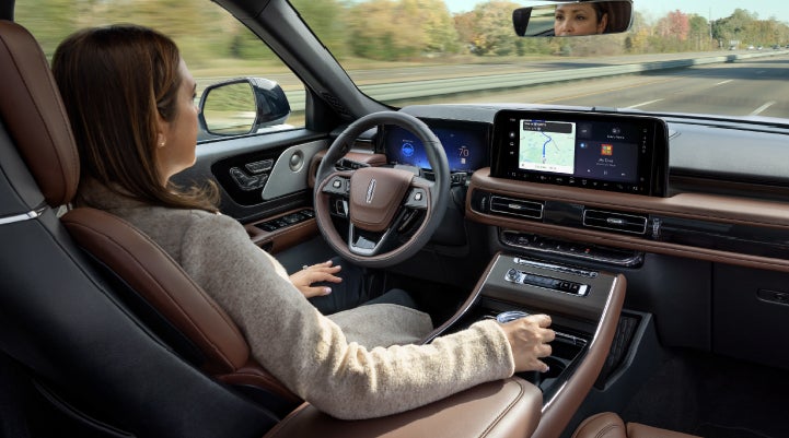 A 2027 Lincoln Aviator® SUV is being driven hands-free on a highway lined with trees. | Steet-Ponte Lincoln in Yorkville NY