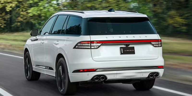 back view of a white 2025 Lincoln Aviator driving down a road