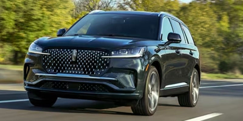 a dark 2025 Lincoln Aviator driving fast up a highway